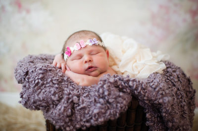 newborn girl with pink headset and purple blanket