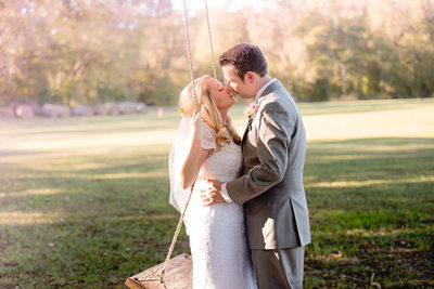 Bride and Groom Kiss on a Swing At Carter Farm