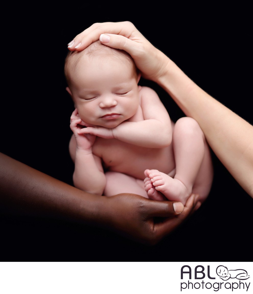 multiracial parents hands holding baby