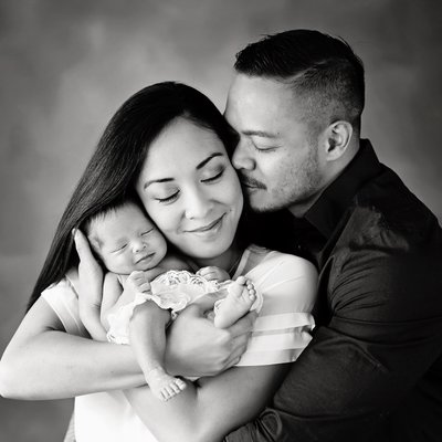 San Diego family photographer with family hugging newborn
