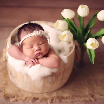 Baby girl in bucket with white tulips