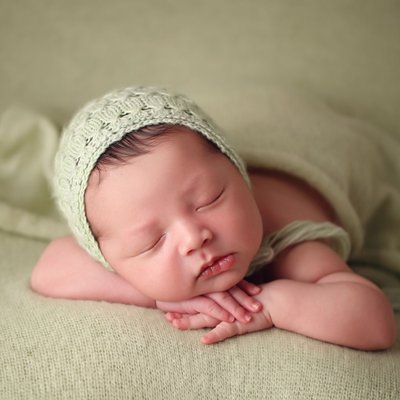 chin on hands newborn pose, baby on green blanket