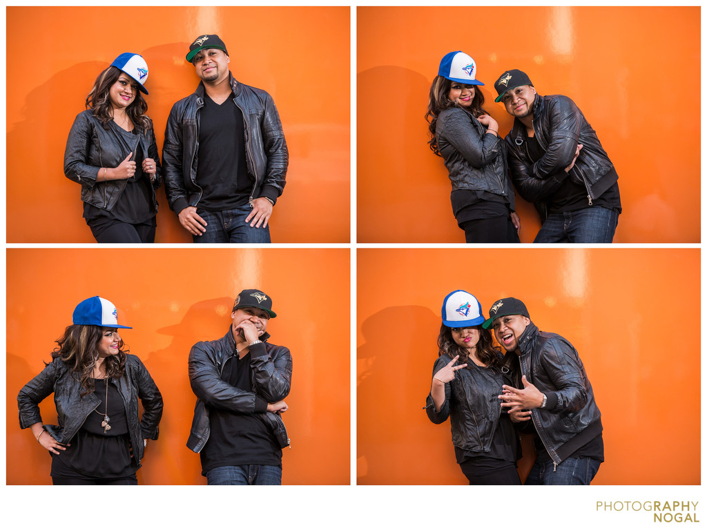 Couple lets loose in sports hats against orange wall