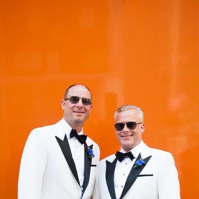 Same Sex Couple Looking Sharp by an Orange Wall
