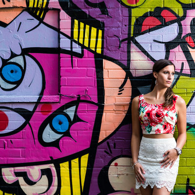 Toronto woman in floral top poses against graffiti wall