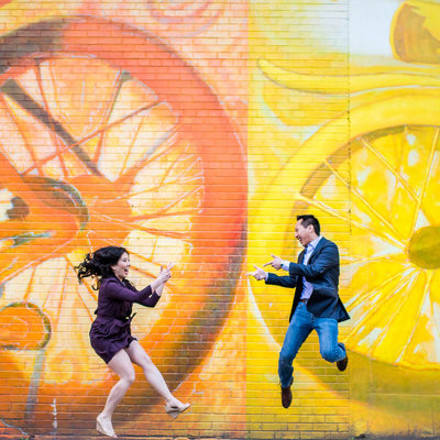 Couple jumping in the air with bike mural behind them