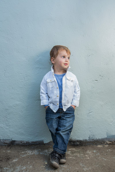 toddler poses in denim and white linen shirt blue wall