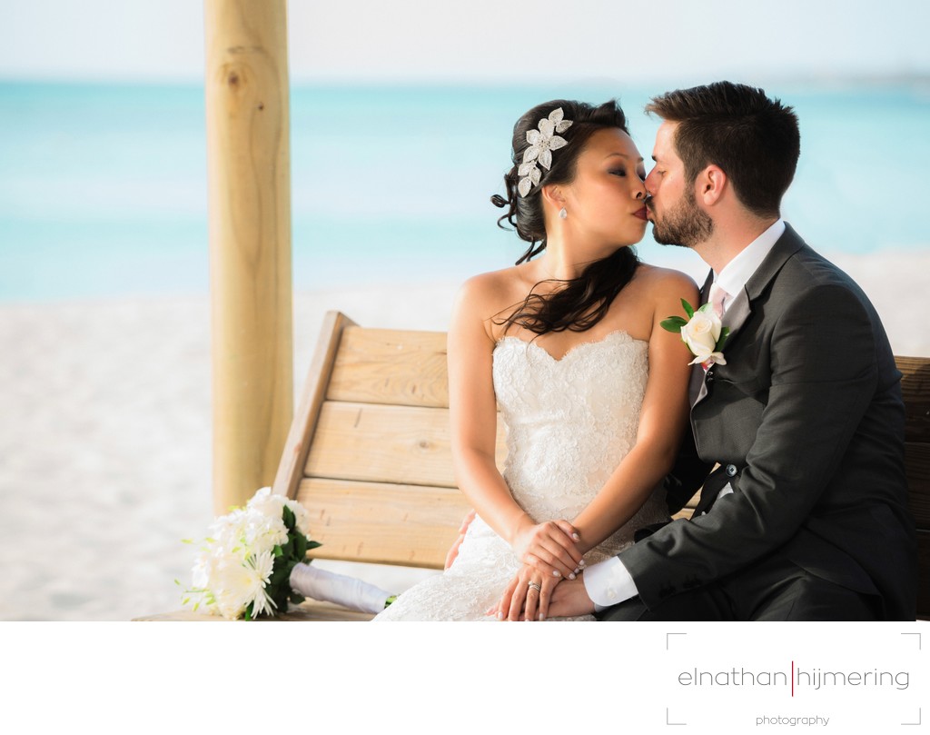 bench kissing bride groom beach
