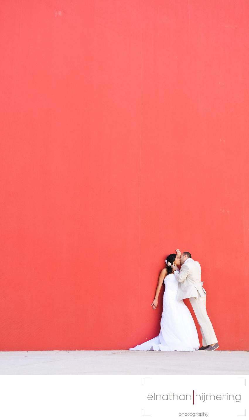 bride groom kissing red wall