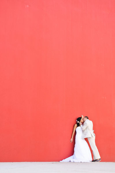 bride groom kissing red wall