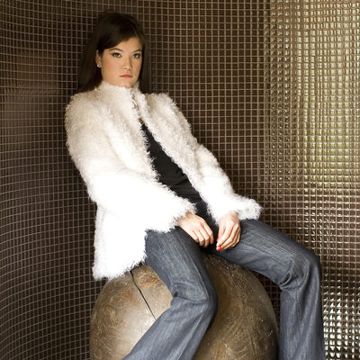 fur jacket photographed on a model sitting on a wooden ball