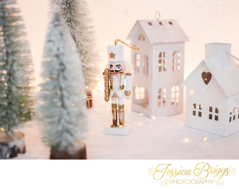 Christmas nutcracker toy soldier figurine ornament in white. Decoration for new year. Nutcracker on the white sparkling background with conifers. Advent concept with bokeh lights.