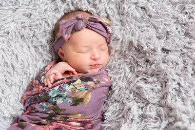 Sleeping baby girl in purple flowered swaddle