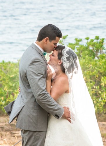 Beach destination wedding: Groom kisses the bride