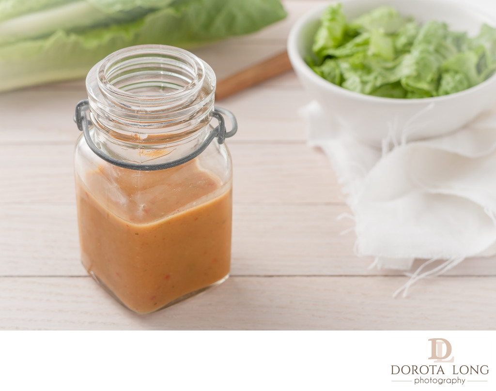 salad dressing in a glass container on light wooden background