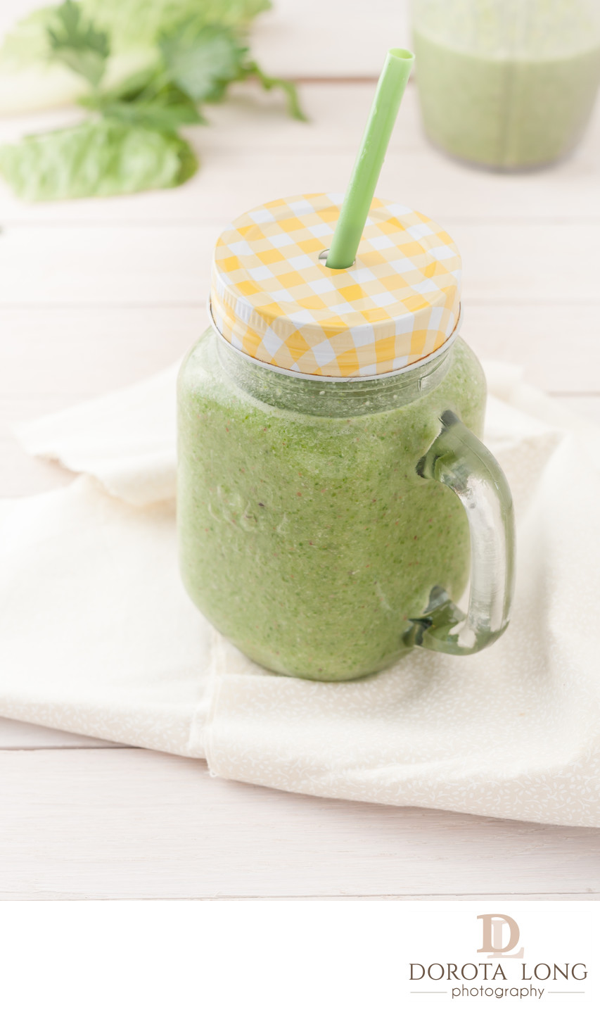 green smoothie in a glass jar with lid and a straw