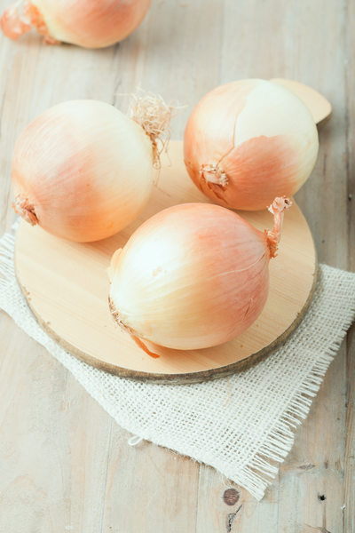 three whole onions on chopping board