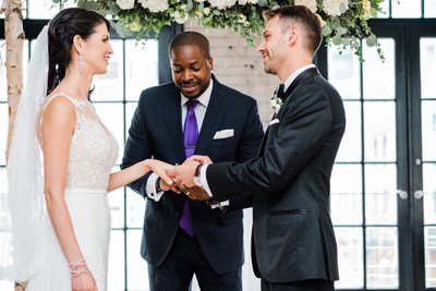 Groom Places Ring on Bride's Hand at Storys Building Wedding