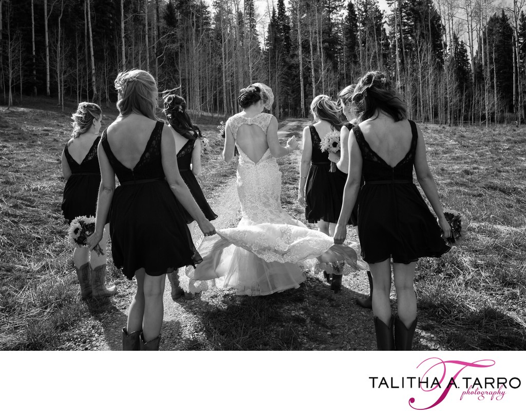 Bridesmaids carrying the dress of the bride as they walk together 
