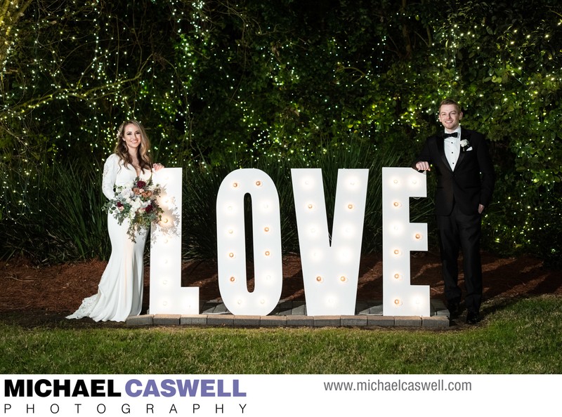 Bride and groom by Love sign at Southern Oaks