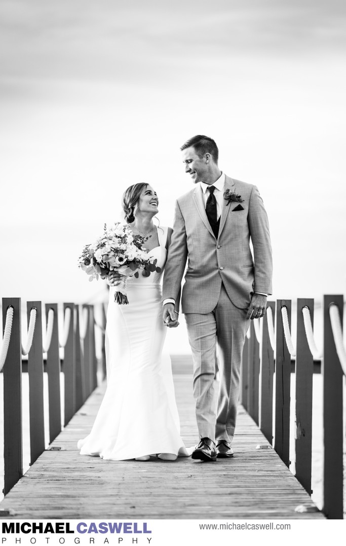 Bride and groom walk along pier