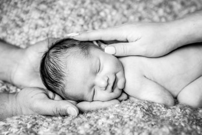 newborn baby sleeping in mom and dad's hands