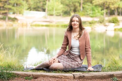 Senior Girl Sitting on Bridge Over Pond