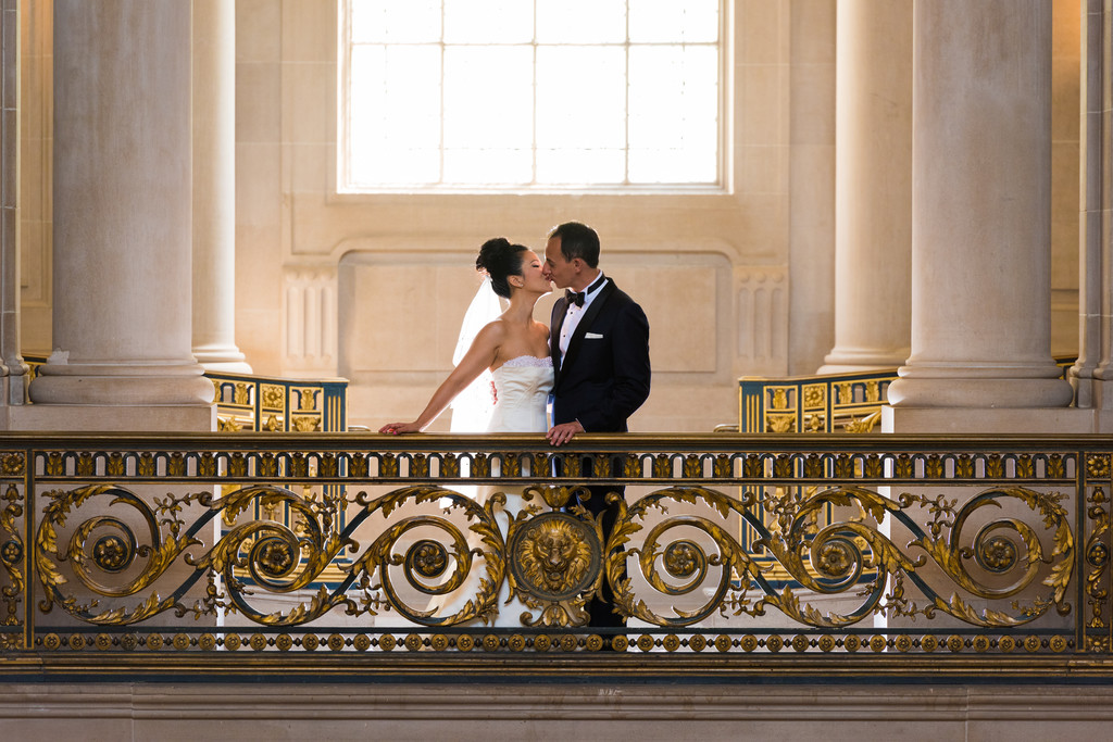 romantic kiss on an elegant 2nd floor balcony with intricate golden railings,