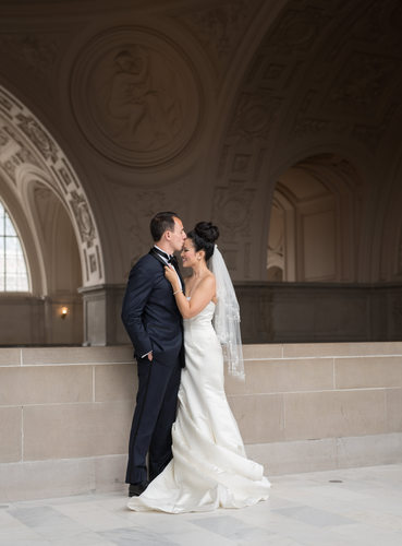 A groom tender kiss on the bride's forehead, San Francisco's City Hall 