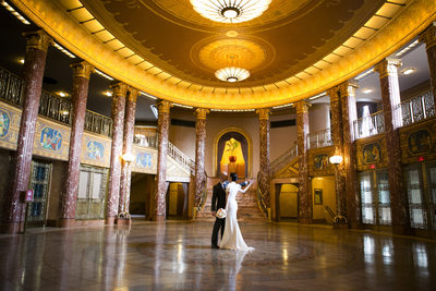 Bride and groom dance alone in Severance Hall, stopping for a kiss