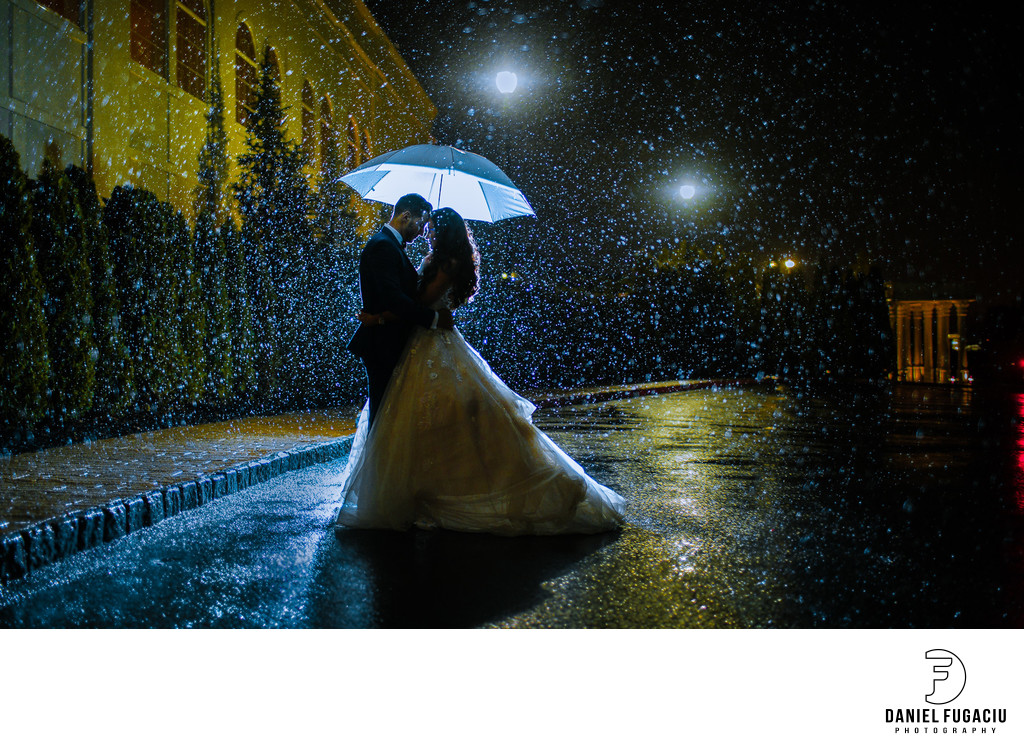 Portrait of Bride and Groom under umbrella in the rain