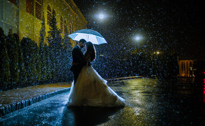 Portrait of Bride and Groom under umbrella in the rain