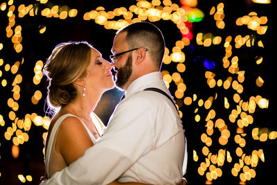 Bride and groom snuggling surrounded by sparkly lights