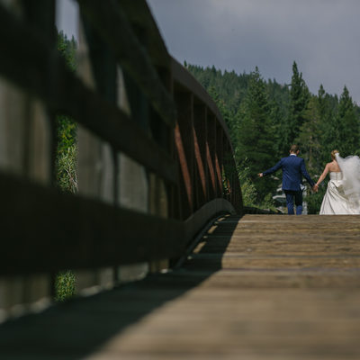 Bride and groom walking on footbridge in Squaw valley
