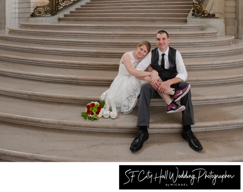 German newlyweds sitting together on the City Hall's Grand Staircase with red shoes