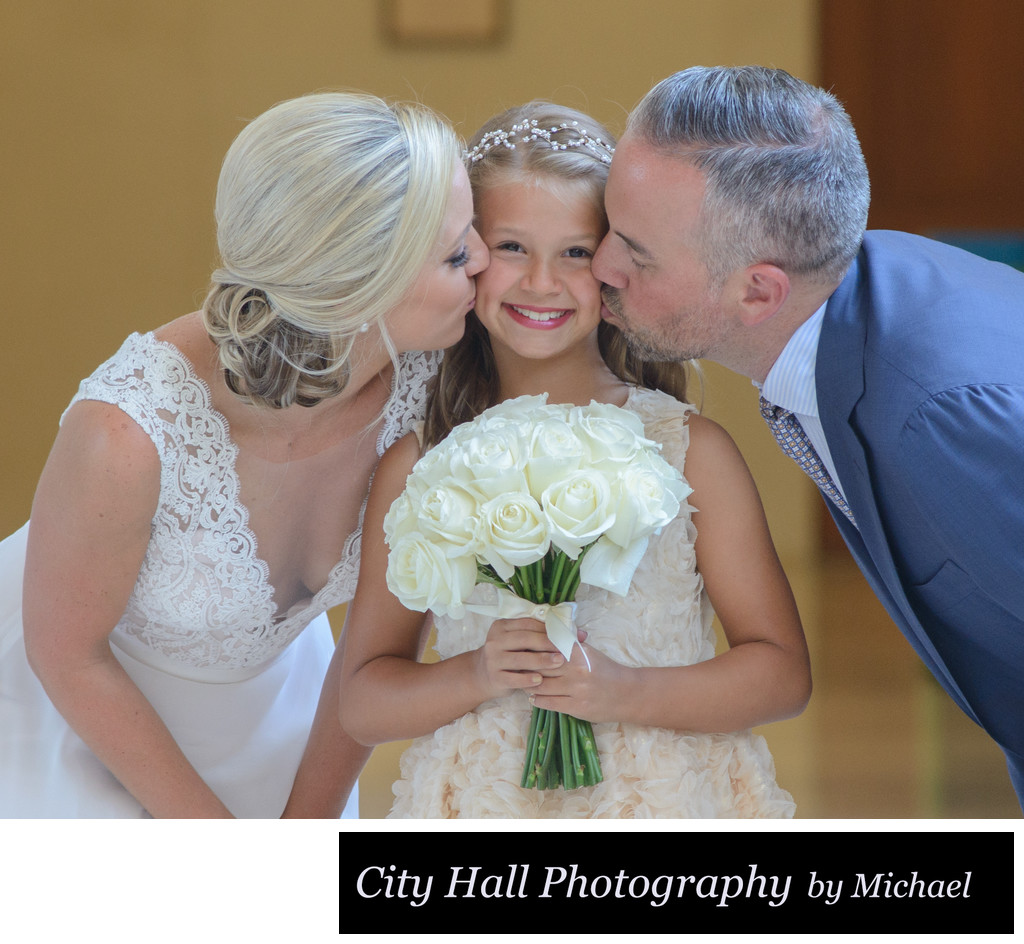 Bride and groom kissing  daughter at SF City Hall with Bouquet