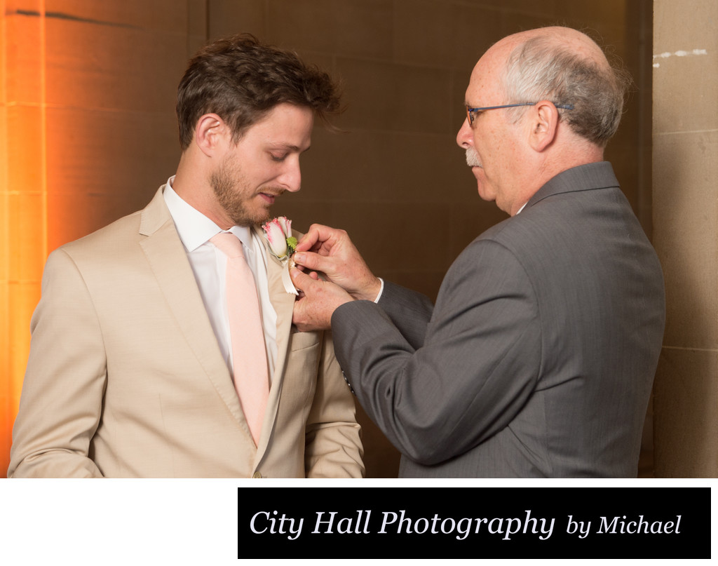 Dad and groom pinning on boutonniere flower  before ceremony