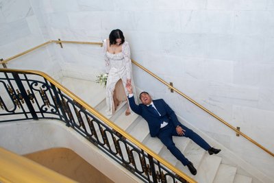 Bride dragging groom up stairs at city hall