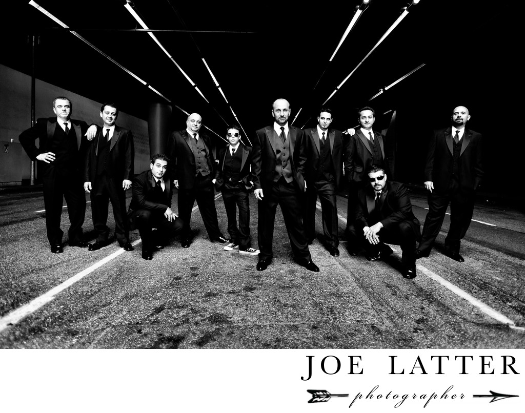 Creative black and white image of large wedding party and groomsmen in a gritty urban location.