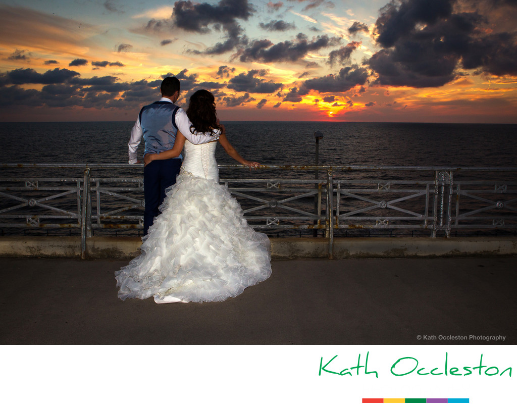 Bride & Groom watching the sun set over the sea