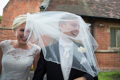 Bride and groom under a windy veil