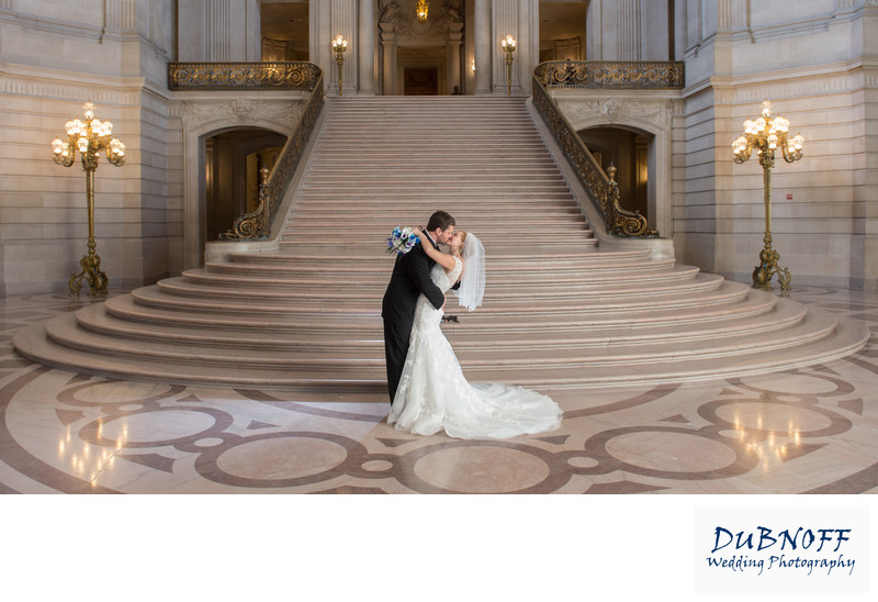 Bride and Groom Kissing in front of the Grand Staircase with beautiful wedding dress