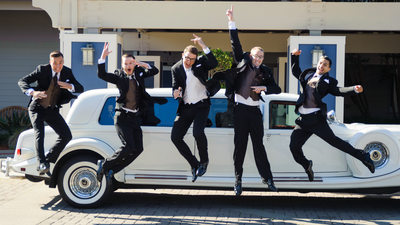 guys wedding jump in front of a limo by the Berkeley Marina