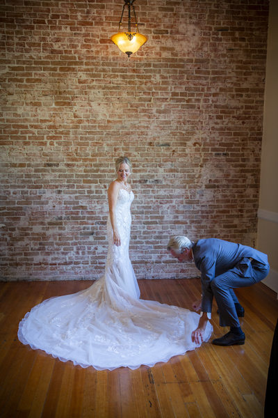 Groom helping his new bride with her dress train