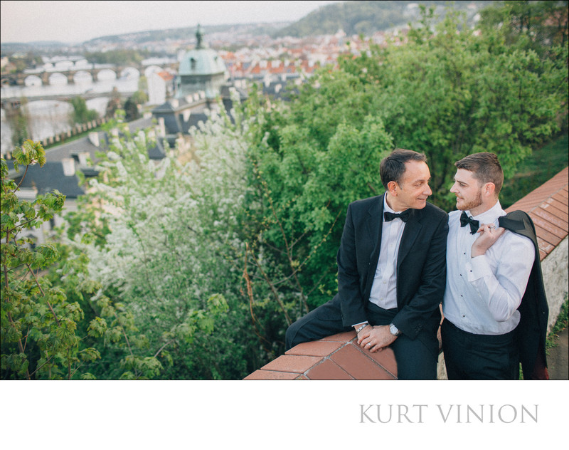 Two men in tuxedos sharing a moment overlooking Prague