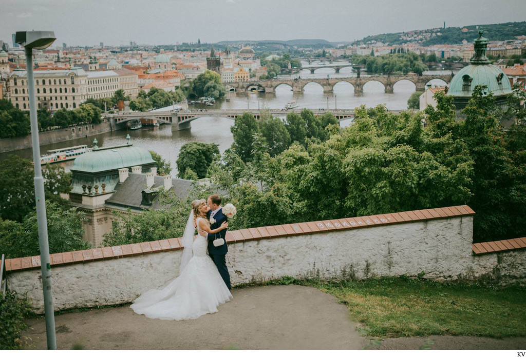 Gorgeous wedding couple embracing above Prague