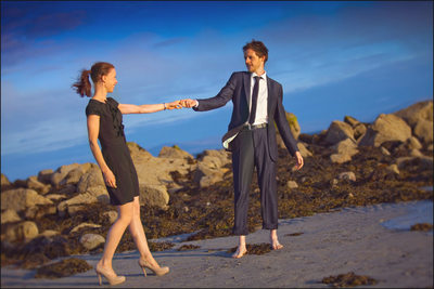holding her by the hand on the beach engagement session