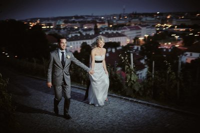 Excited bride led by groom into vineyards above Prague