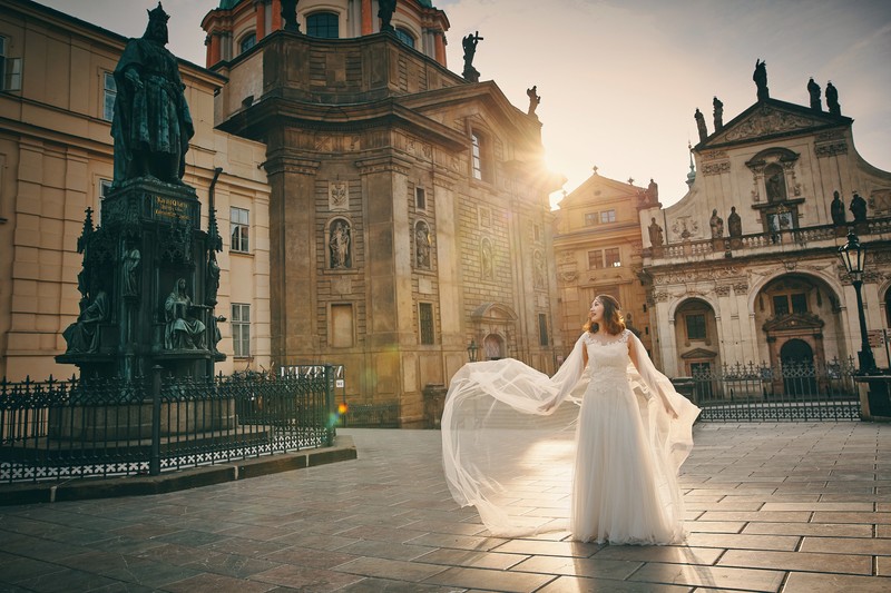 a bride fluffs her veil as the sun flares around her