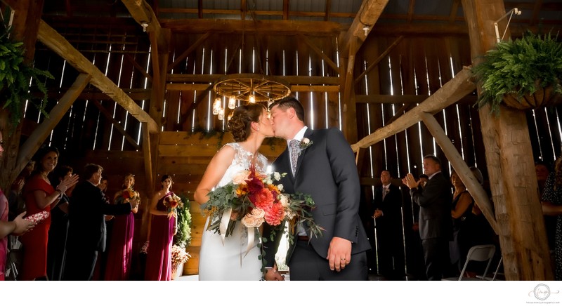 Bride Groom Kissing During the Ceremony Exit in a Barn